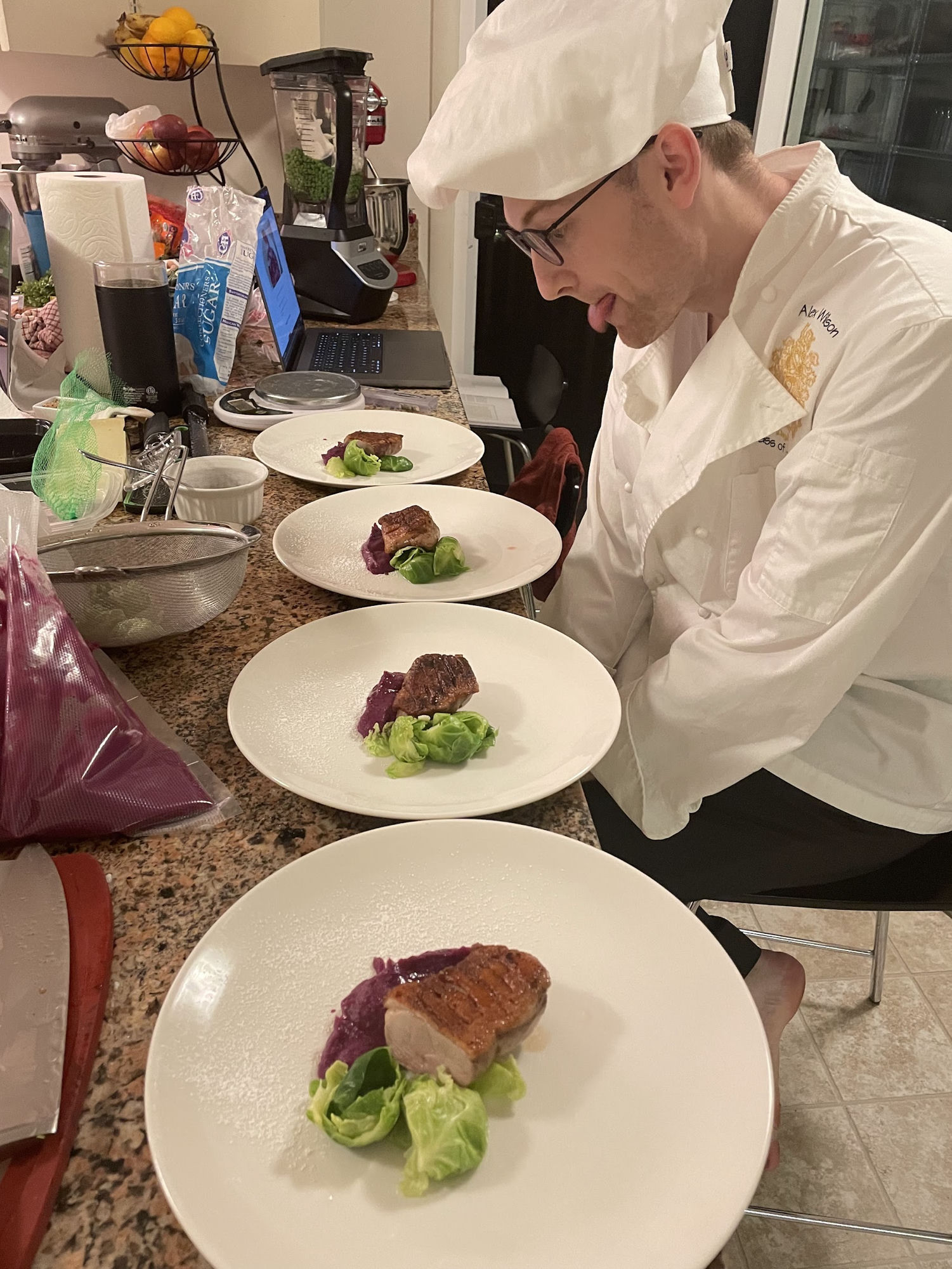 In full chef whites, tongue out in concentration, plating four courses of duck