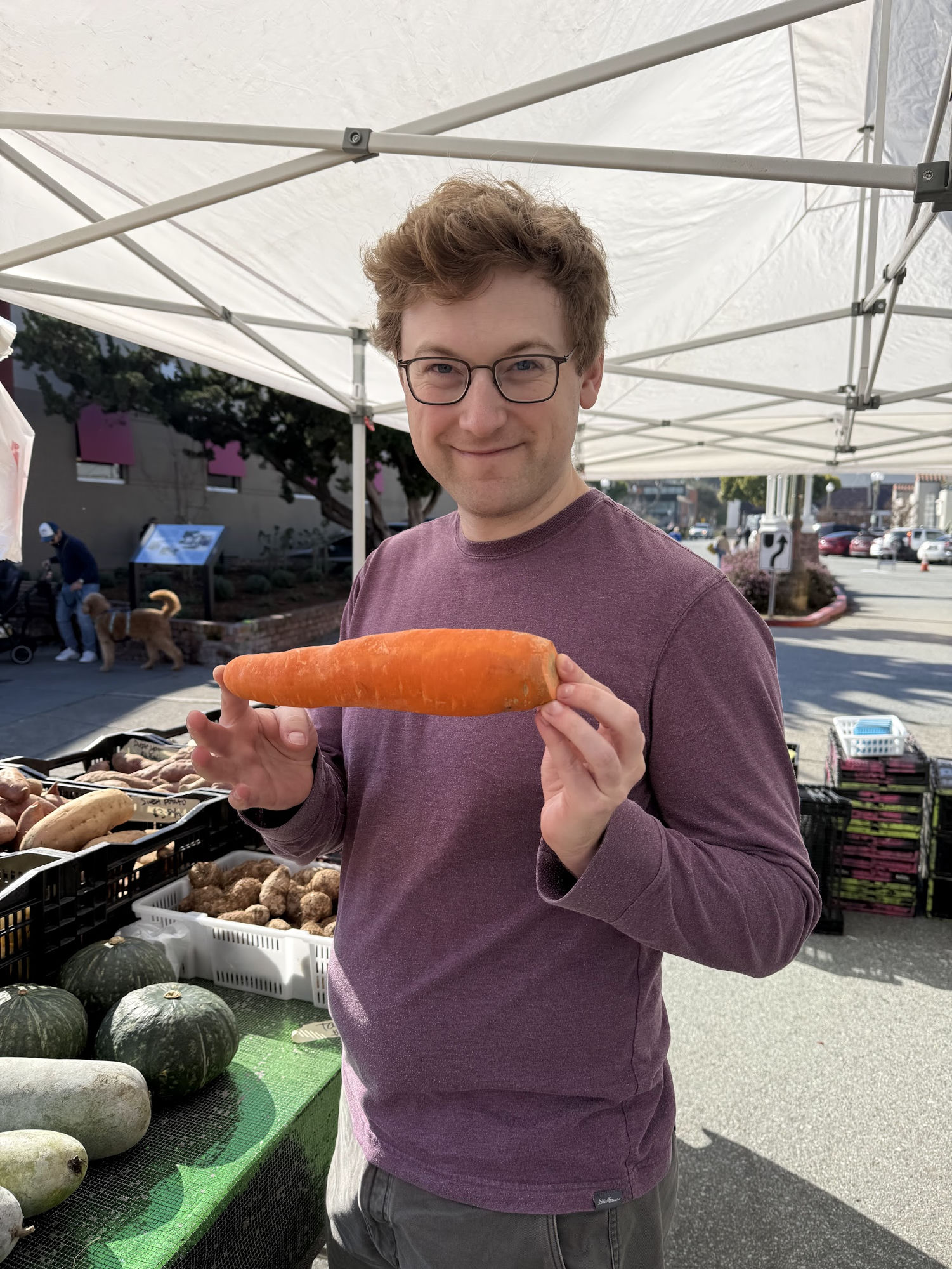 Holding up an impressively large carrot at the farmer's market