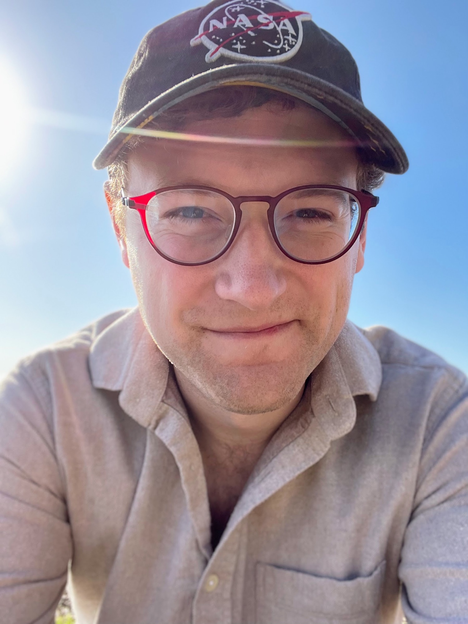 Closeup of Alex in a NASA cap on a sunny day
